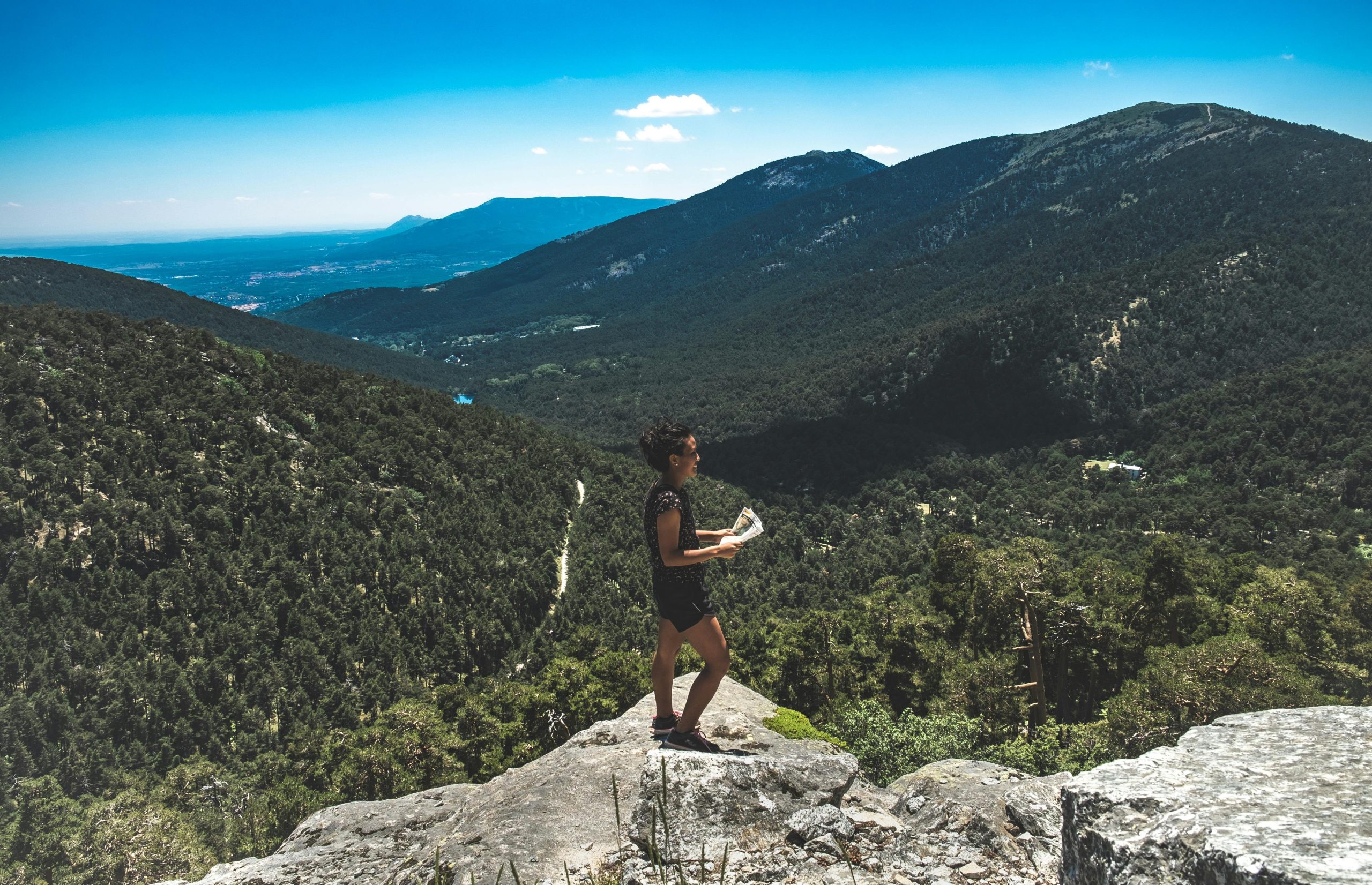 A hiker holding an old-fashioned compass and map under cloudy skies
