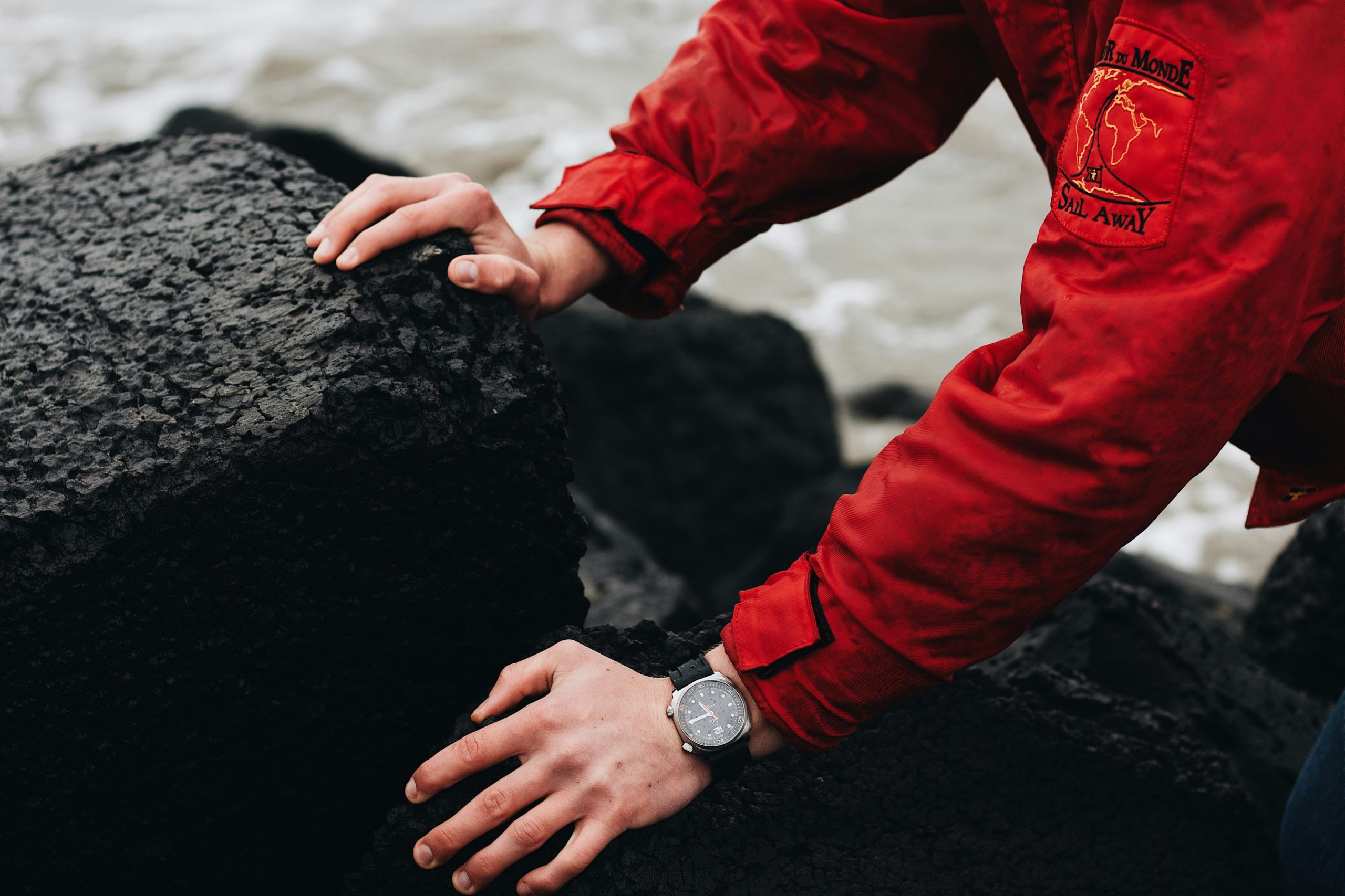 Hiker standing proudly atop a peak wearing a trail watch against a breathtaking mountain backdrop.