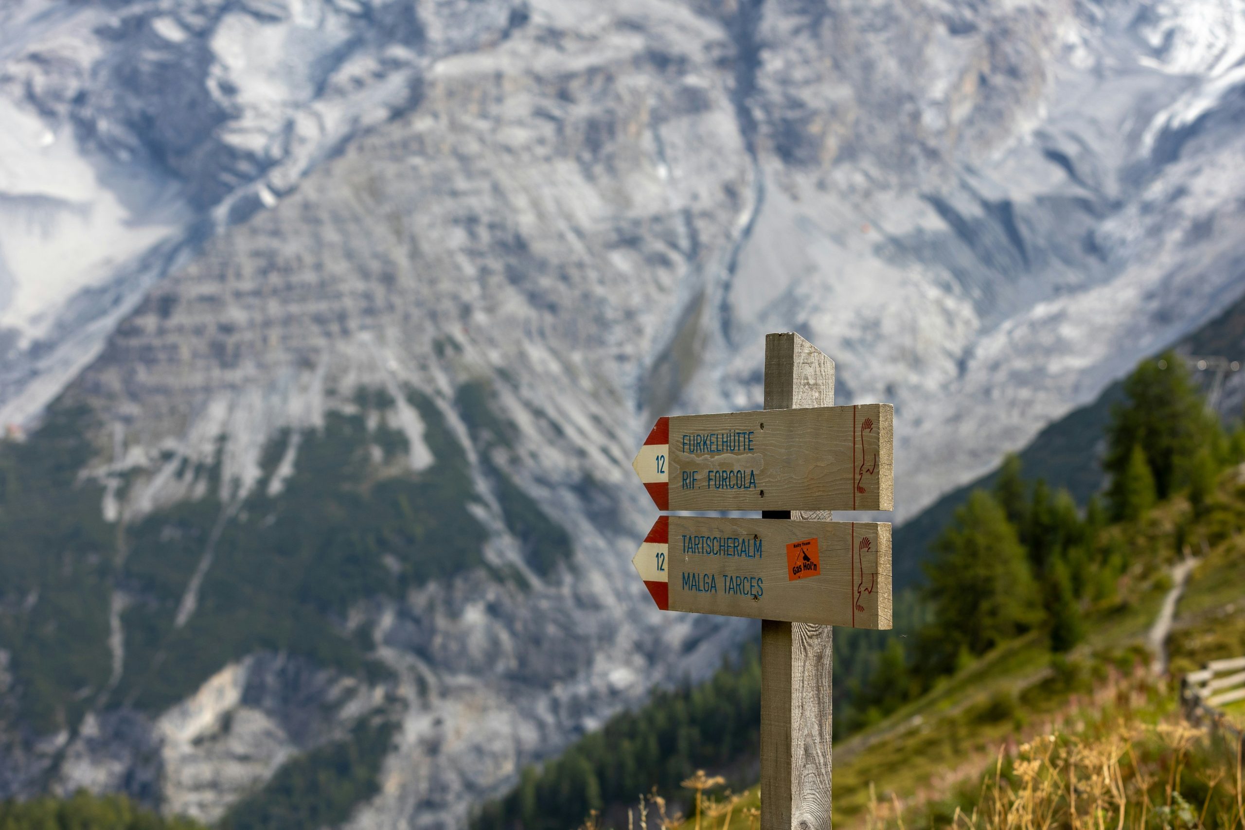 Two hikers smiling and checking their smartwatches under clear blue skies.